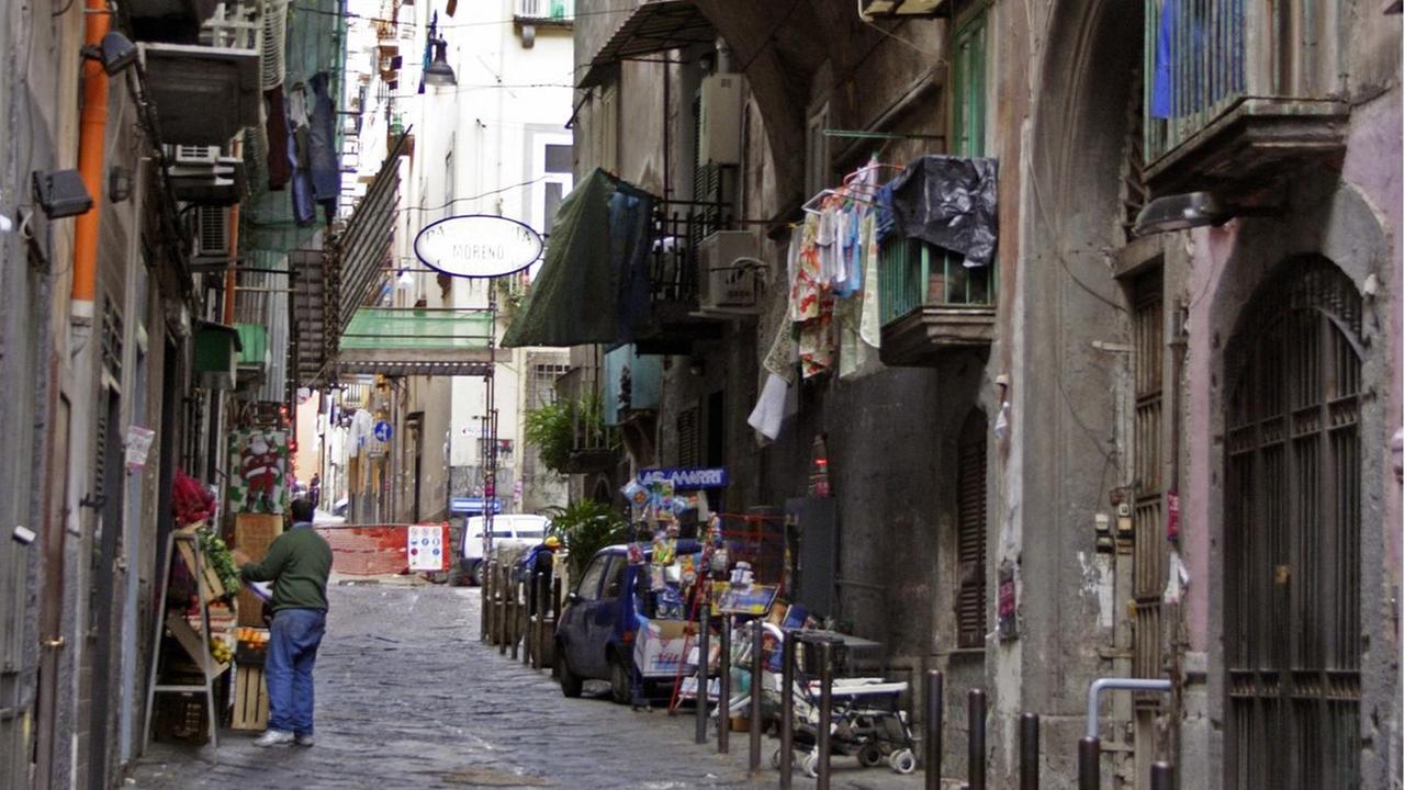 Blick in eine Straße mit altmodischem Straßenpflaster und Torbogen, in Italien, Neapel