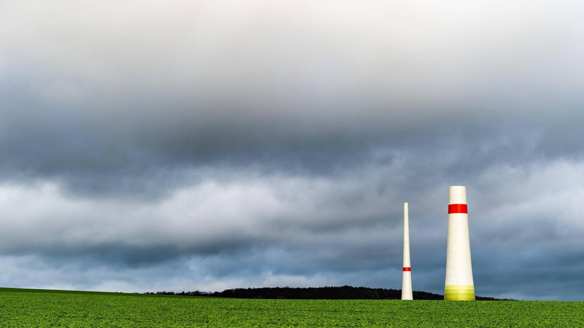 Teile eines noch nicht fertiggestellten Windrads in Jühnde, Niedersachsen stehen vor dunklen Wolken. Teile eines noch nicht fertiggestellten Windrads in Jühnde, Niedersachsen stehen vor dunklen Wolken.