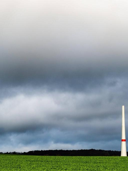 Teile eines noch nicht fertiggestellten Windrads in Jühnde, Niedersachsen stehen vor dunklen Wolken.