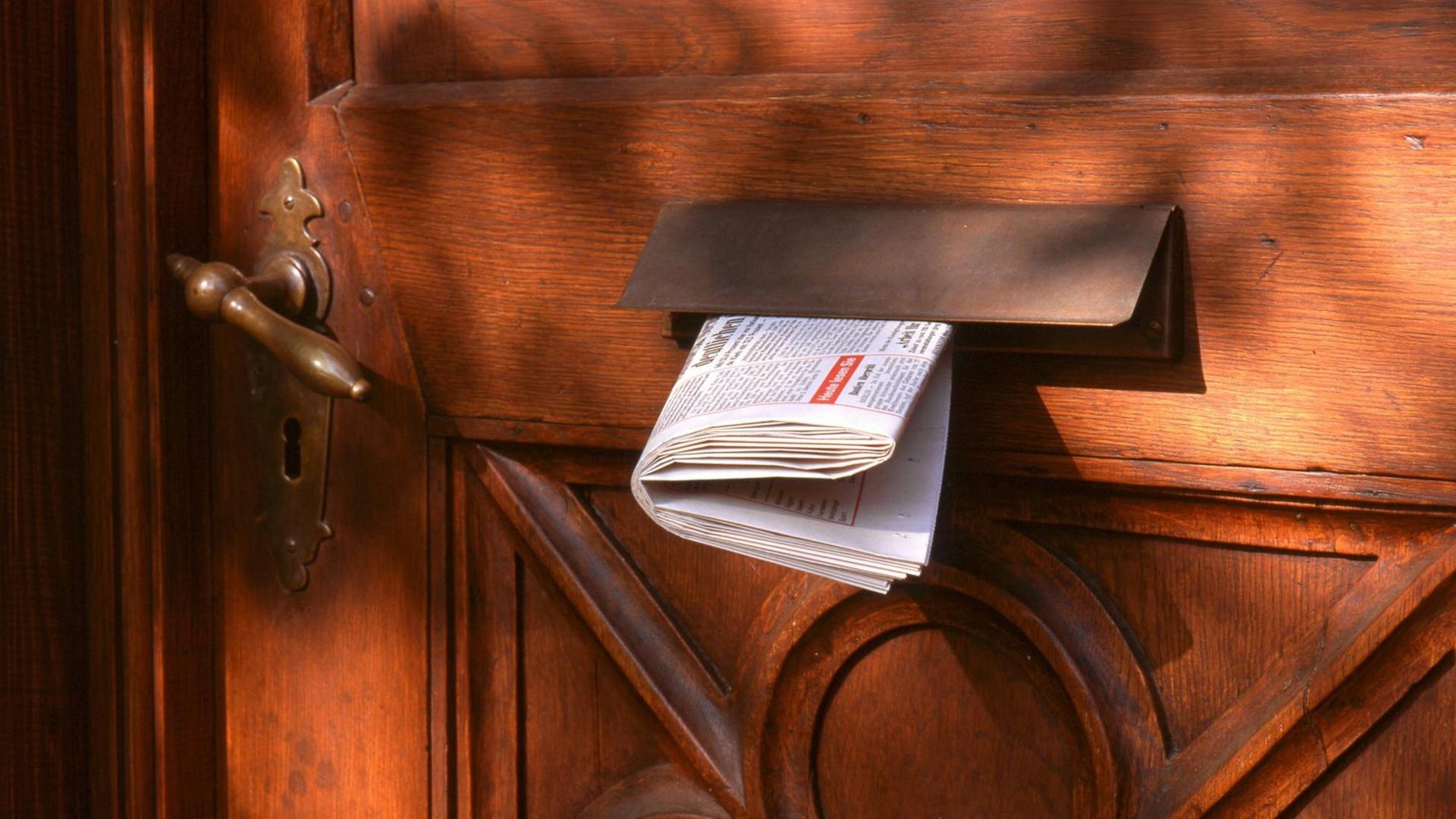 Eine Tageszeitung steckt in einem Briefkasten. Eine Tageszeitung steckt in einem Briefkasten.
