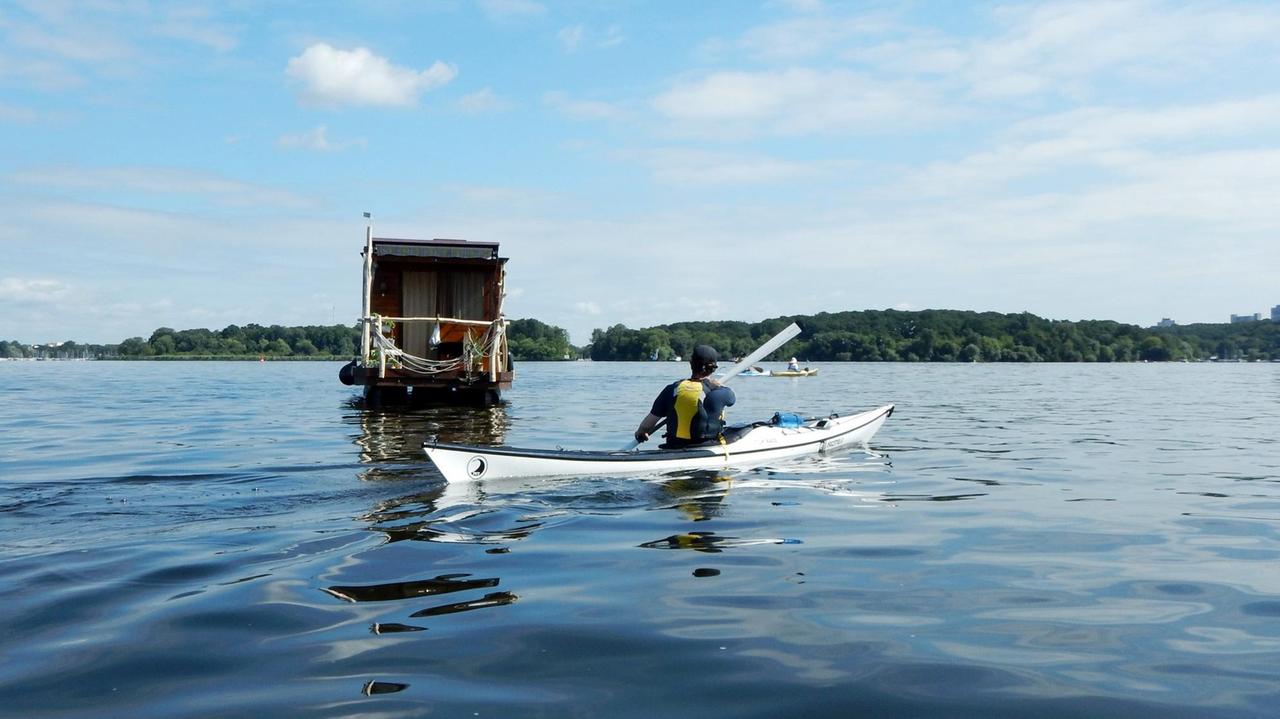 Ein Kajak und ein Hausboot unterwegs auf dem Wasser, zwischen Havel und Stößensee in Berlin-Spandau. Ein Kajak und ein Hausboot unterwegs auf dem Wasser, zwischen Havel und Stößensee in Berlin-Spandau.