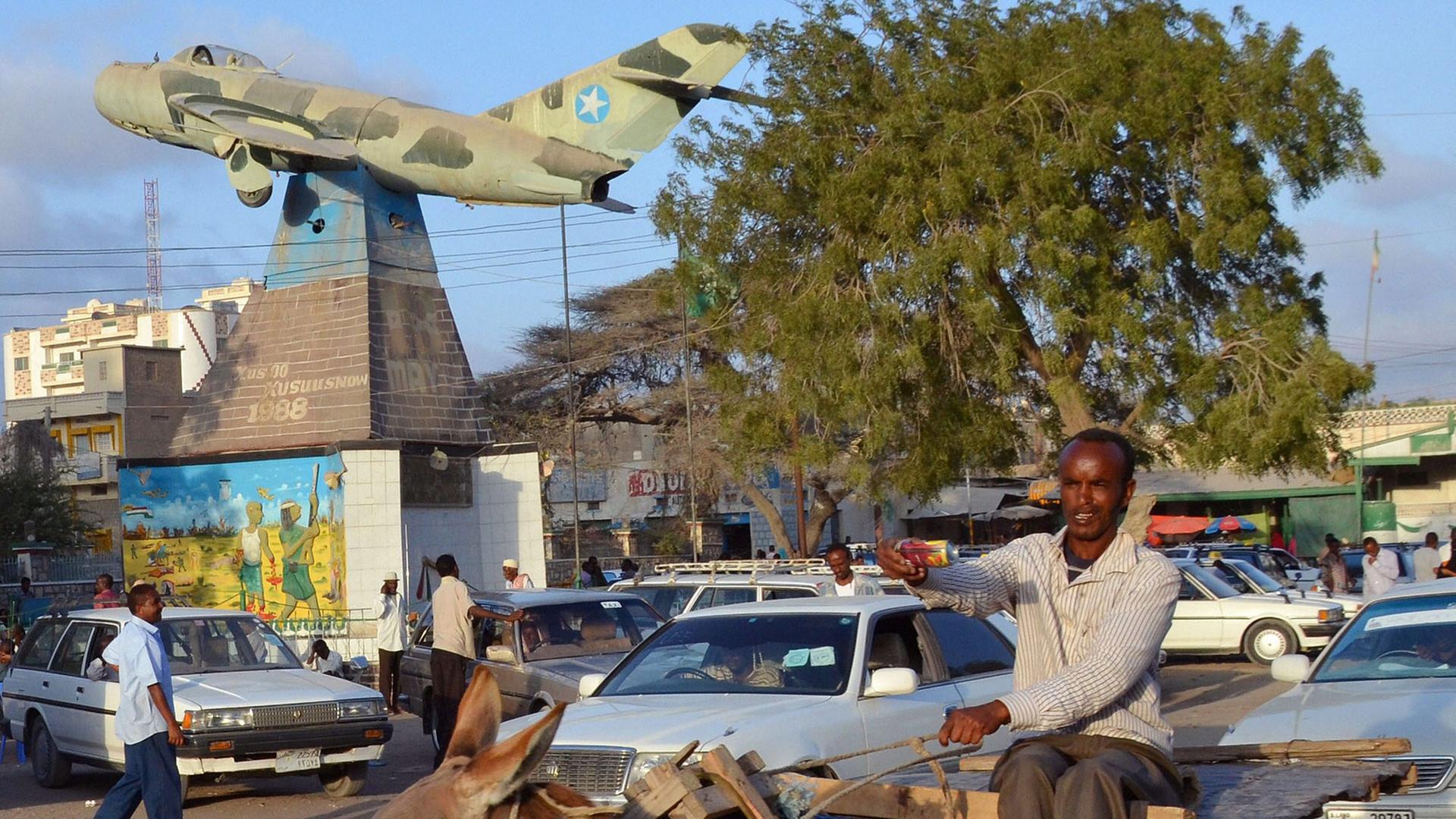 Die somalische Hauptstadt Hargeisa. Die Ein Mann sitzt auf einem Esel und reitet durch eine befahrene Straße. Die somalische Hauptstadt Hargeisa. Die Ein Mann sitzt auf einem Esel und reitet durch eine befahrene Straße.