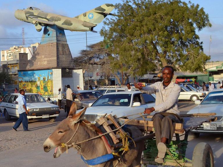 Die somalische Hauptstadt Hargeisa. Die Ein Mann sitzt auf einem Esel und reitet durch eine befahrene Straße.
