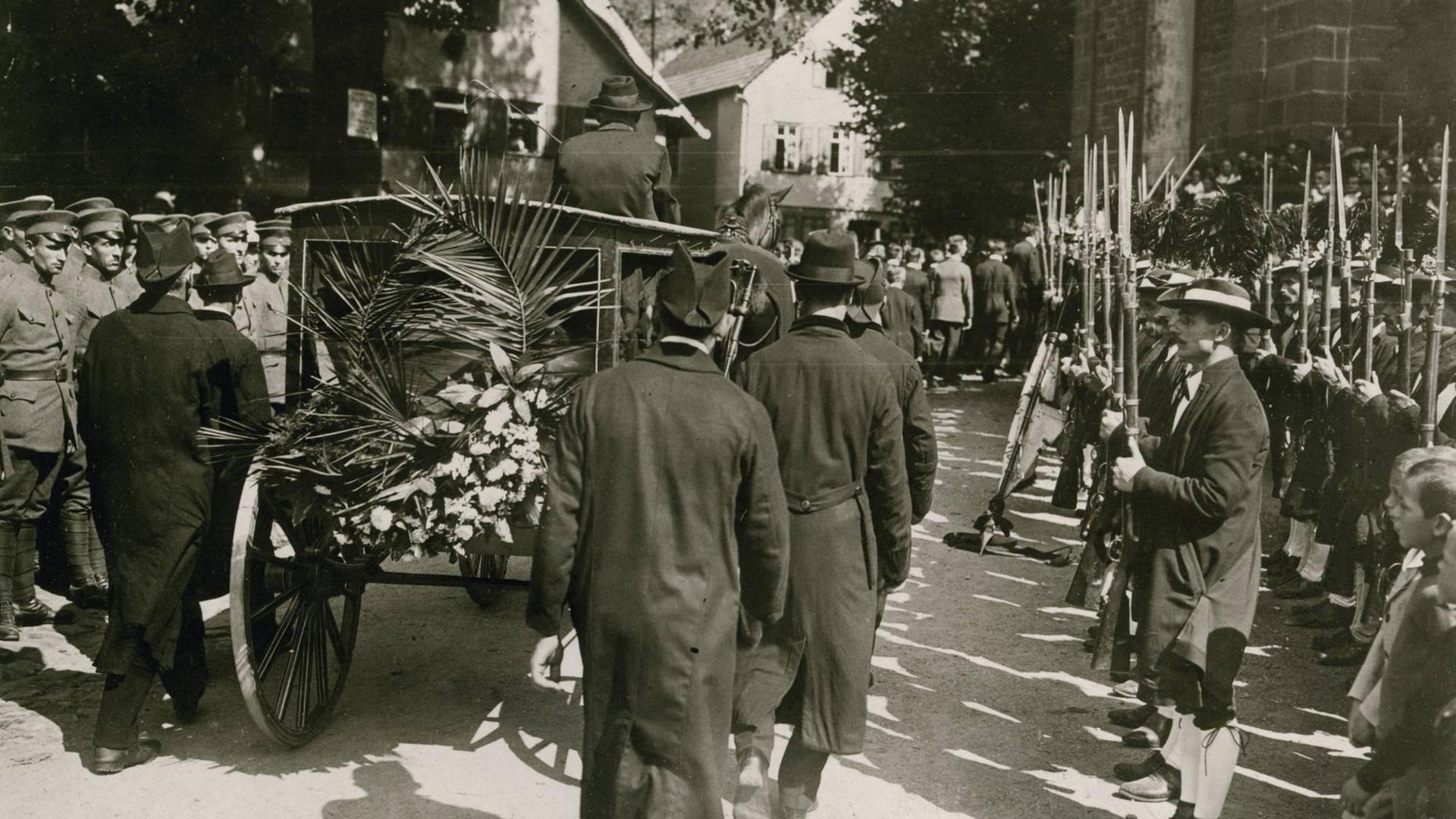 Bei den Beisetzungsfeierlichkeiten für Matthias Erzberger passiert der Leichenwagen eine Ehrenformation Schwarzwälder Schützen. Foto, August 1921 (Robert Sennecke) Bei den Beisetzungsfeierlichkeiten für Matthias Erzberger passiert der Leichenwagen eine Ehrenformation Schwarzwälder Schützen. Foto, August 1921 (Robert Sennecke)