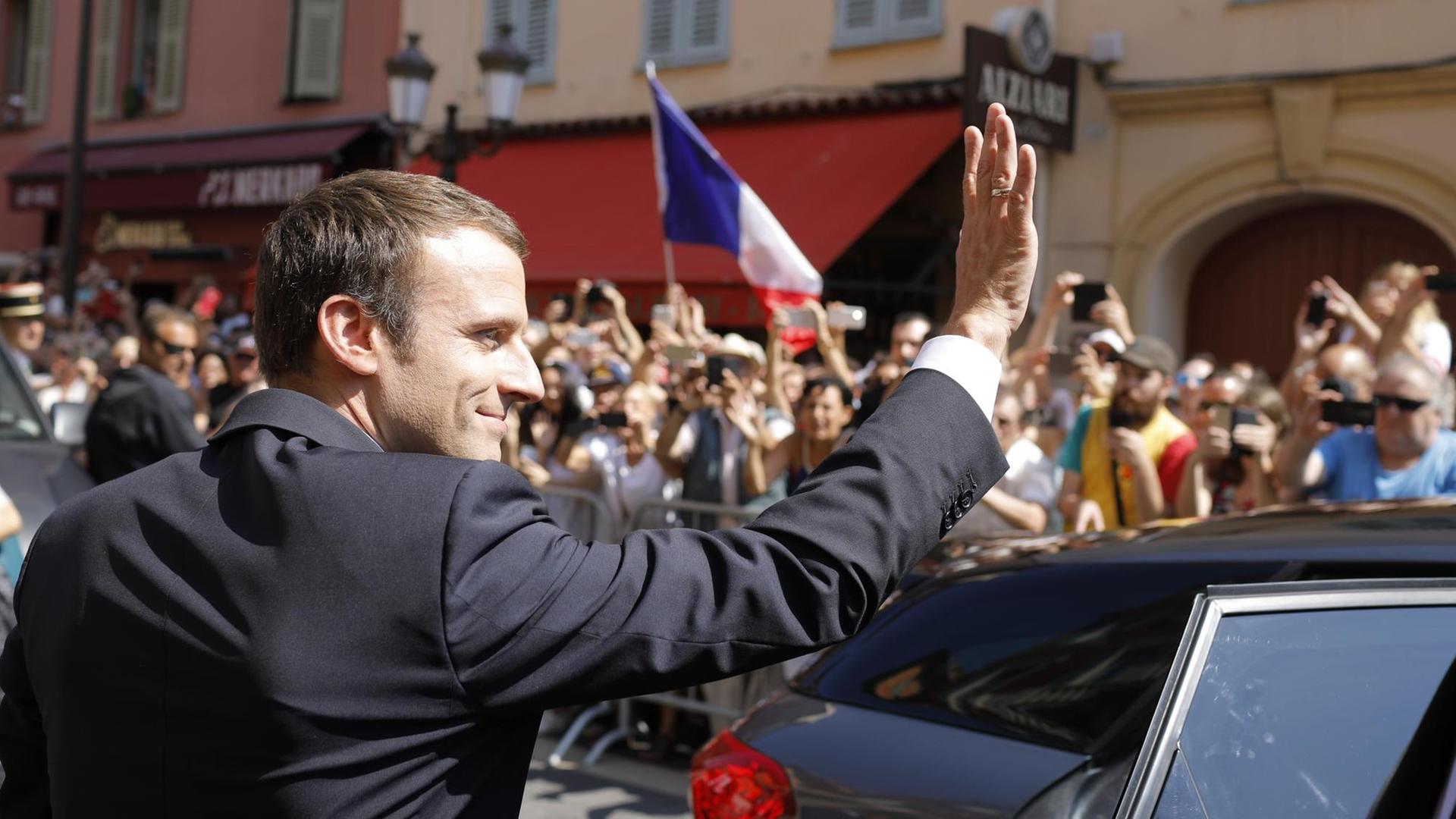 Der französische Präsident Emmanuel Macron winkt der Menge bei seiner Ankunft in Nizza/Südfrankreich zu. Er besucht den Ort anlässlich des 1. Jahrestages des Massakers, bei dem damals 86 Menschen getötet worden waren.