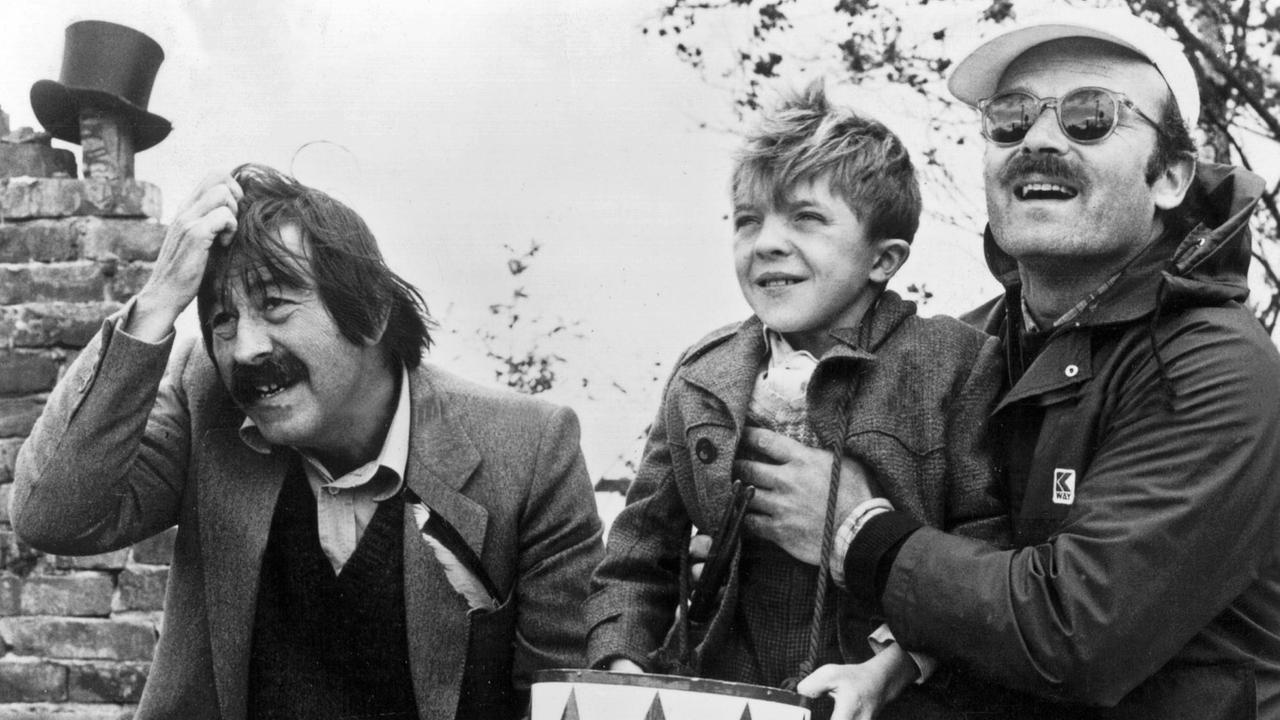 Auf einer schwarzweissen Aufnahme sind Günter Grass, David Bennent (als Blechtrommler Oskar Matzerath) und der Regisseur Volker Schlöndorff zu sehen. Auf einer schwarzweissen Aufnahme sind Günter Grass, David Bennent (als Blechtrommler Oskar Matzerath) und der Regisseur Volker Schlöndorff zu sehen.