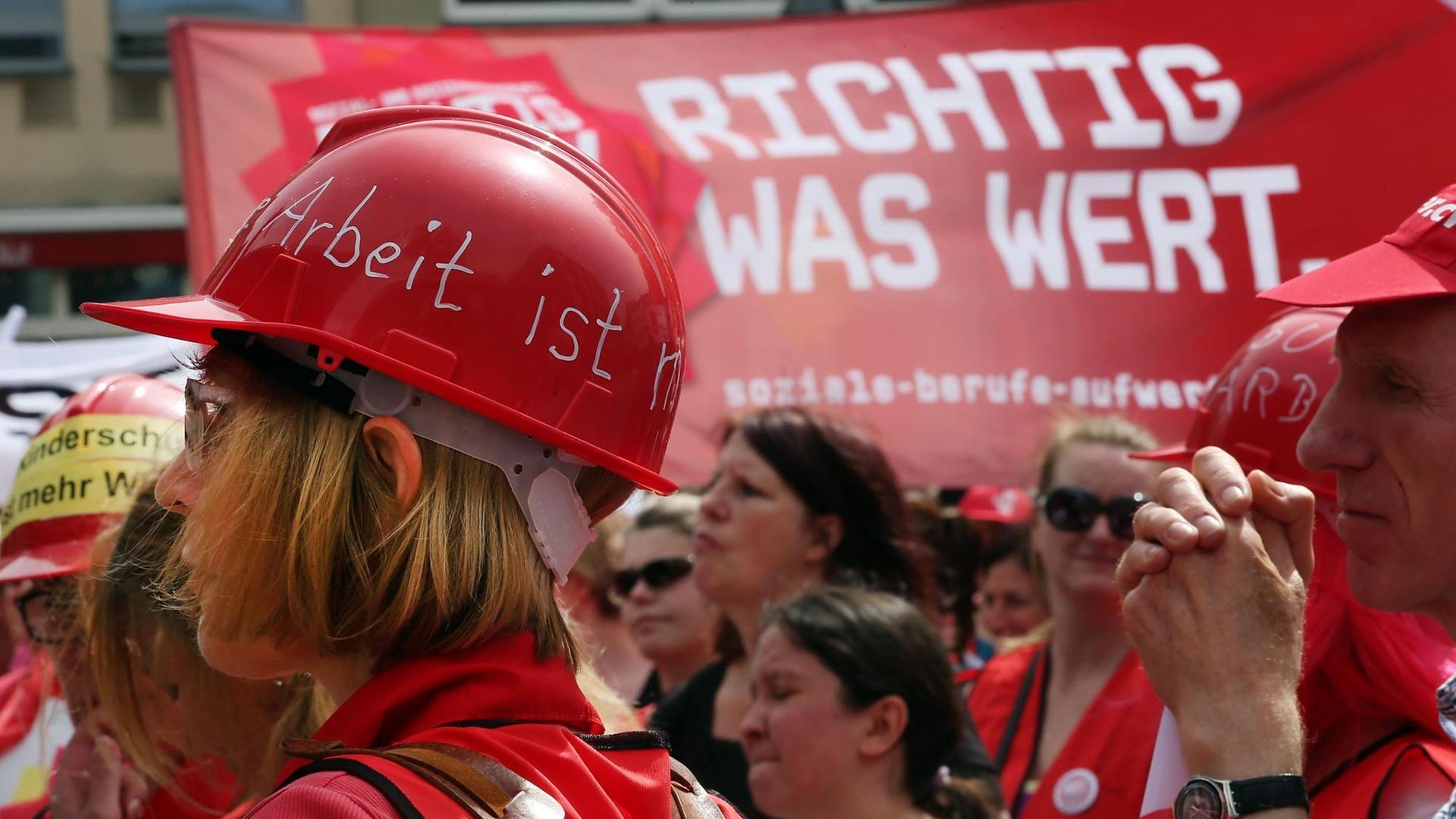 Erzieher und Erzieherinnen mit roten Plastikhelmen beteiligen sich an einer Demonstration.