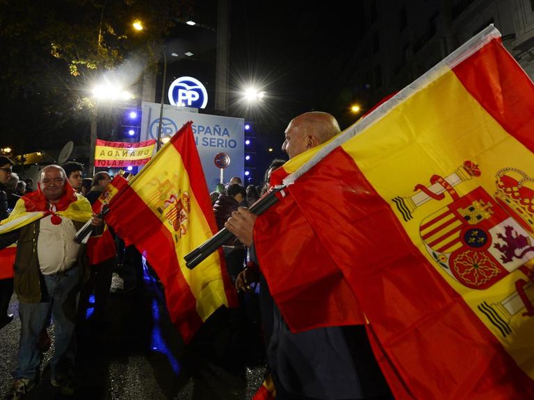 Unterstützer der Volkspartei (PP) schwenken spanische Flaggen vor der Parteizentrale in Madrid, nachdem erste Ergebnisse der Parlamentswahl bekannt wurden.