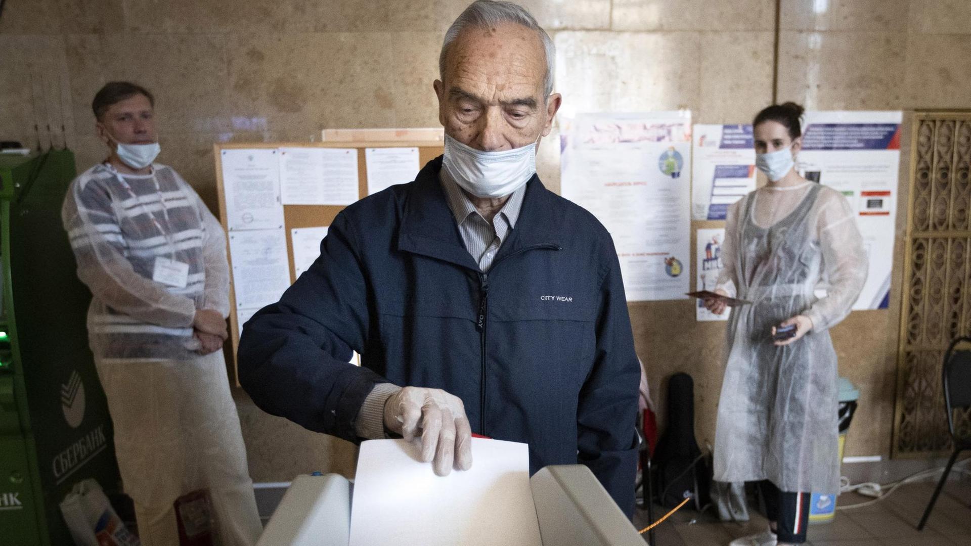 Russland, Moskau: Ein Wähler, der einen Mundschutz und Handschuhe zum Schutz vor dem Coronavirus trägt, wirft seinen Stimmzettel in einem Wahllokal in eine Wahlurne. Russland, Moskau: Ein Wähler, der einen Mundschutz und Handschuhe zum Schutz vor dem Coronavirus trägt, wirft seinen Stimmzettel in einem Wahllokal in eine Wahlurne.