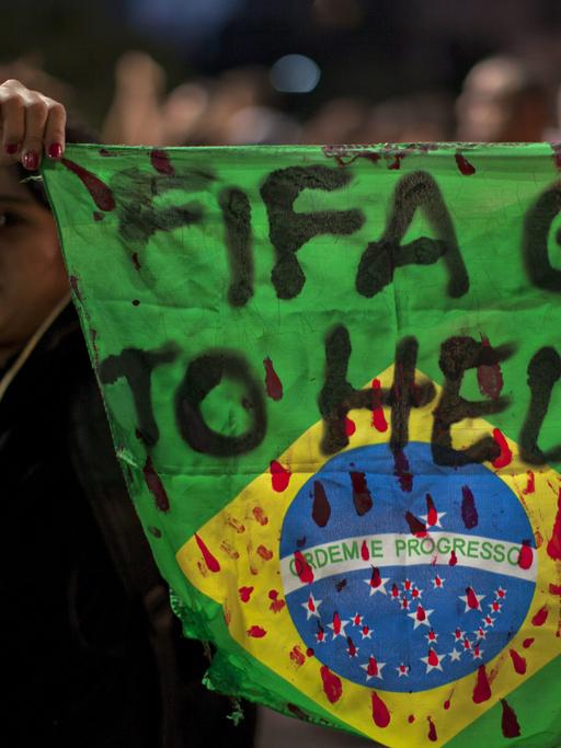 Eine Demonstrantin hält in Sao Paula eine Fahne Brasiliens mit der Aufschrift "Fifa, fahre zur Hölle!" in die Höhe.