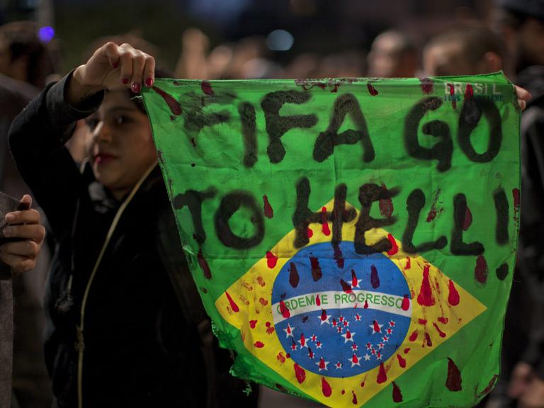 Eine Demonstrantin hält in Sao Paula eine Fahne Brasiliens mit der Aufschrift "Fifa, fahre zur Hölle!" in die Höhe.