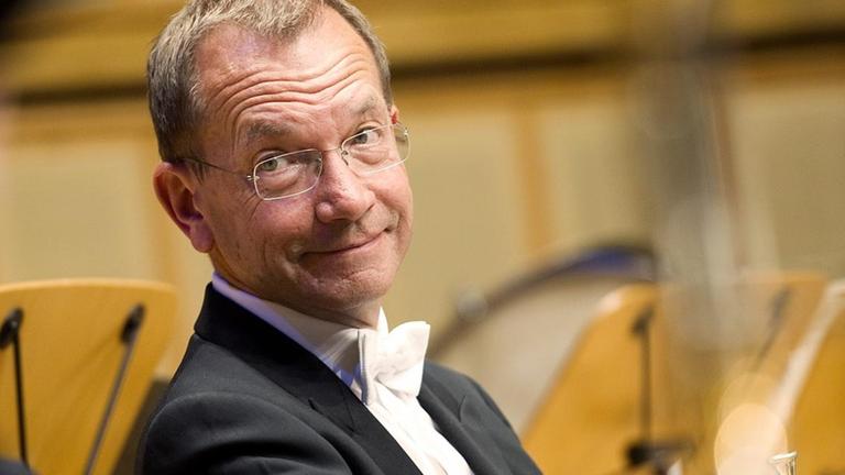 Mann im Frack sitzt mit Horn im Orchester Mann im Frack sitzt mit Horn im Orchester