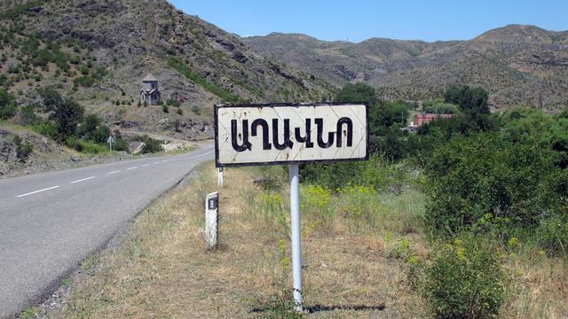 Ein Schild weist in Armenien an der Straße von Goris nach Stepanakert in armenischer Schrift auf einen Ort hin.