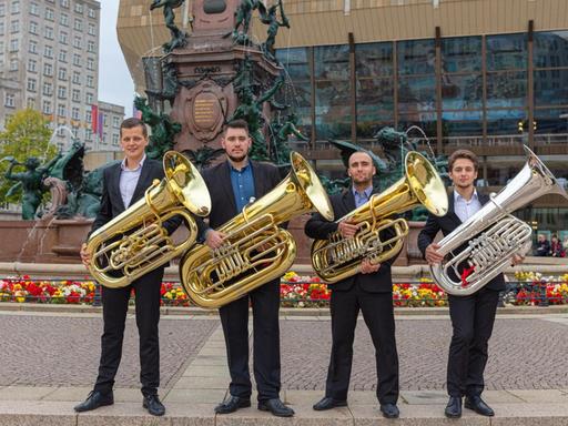 Vier Musiker stehen mit ihren Instrumenten vor dem Gewandhaus Leipzig