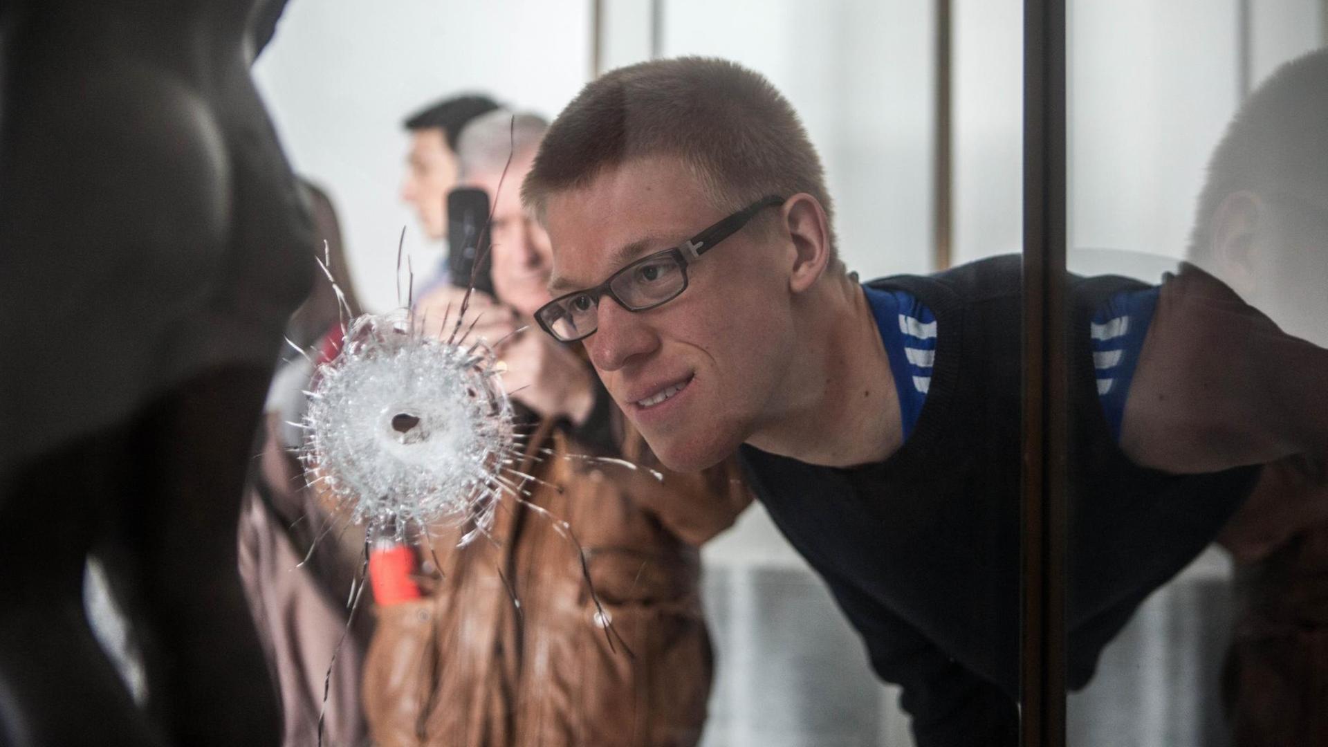 Ein Besucher betrachtet ein Einschussloch in einer Museumsvitrine. Ein Besucher betrachtet ein Einschussloch in einer Museumsvitrine.