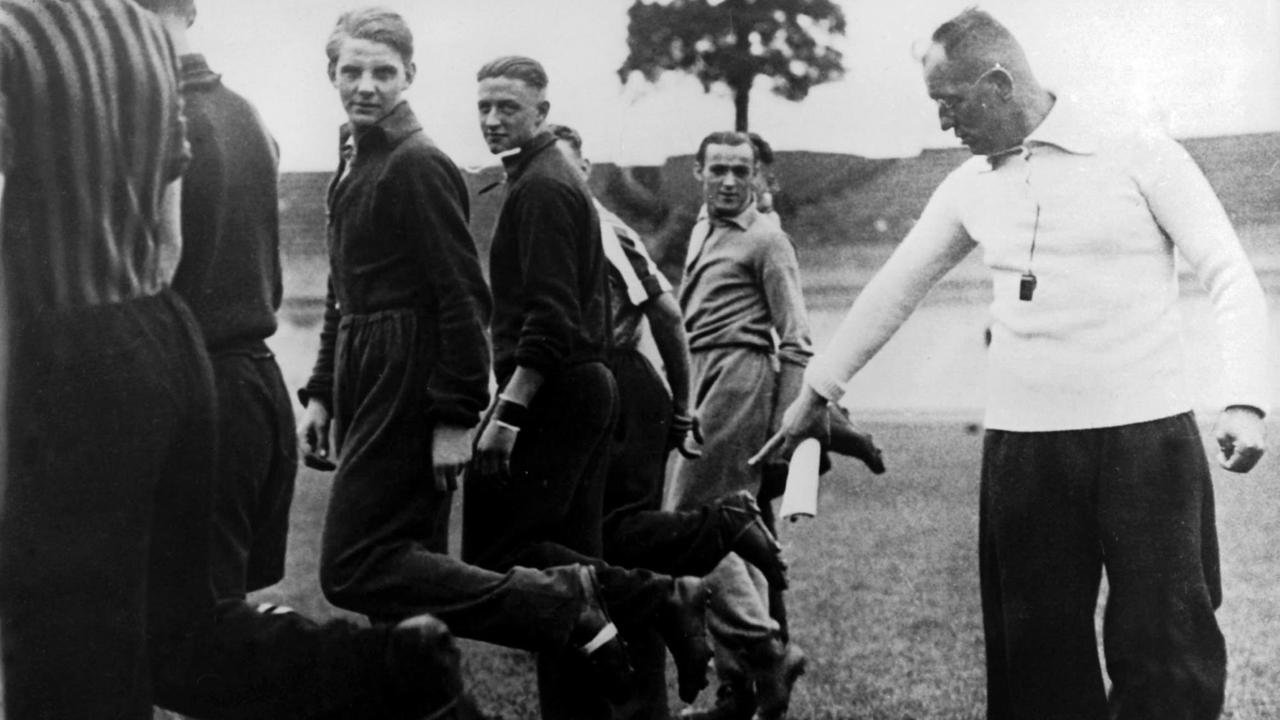 Der deutsche Fußballnationaltrainer Otto Nerz (r.) begutachtet im Training die Schuhe der Spieler (undatierte Archivaufnahme).