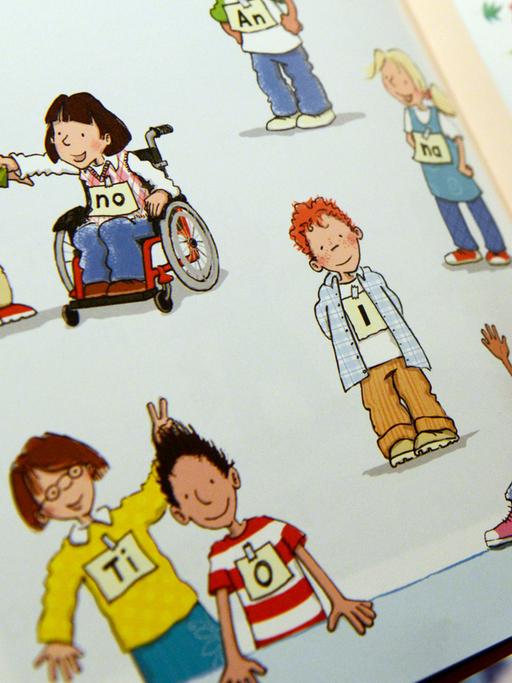 Ein Schulbuch, ein Kind steht, das andere sitzt im Rollstuhl. Kindern soll so das gemeinsame Lernen von nicht behinderten und behinderten Schülern vermittelt werden.