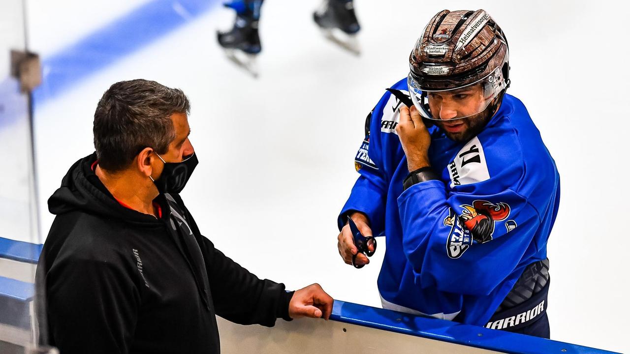 Erstes Eistraining der Saison der Iserlohn Roosters am 01.12.2020. Ein Eishockeyspieler und ein Mann an der Bande.