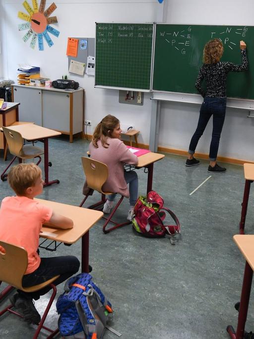 Schülerinnen und Schüler der Klasse 4c der Robert-Schumann-Grundschule sitzen mit Abstand zueinander im Unterricht bei ihrer Lehrerin Sylke Wassmann