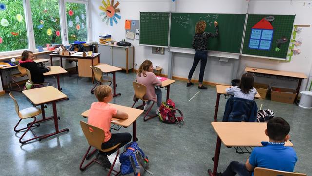 Schülerinnen und Schüler der Klasse 4c der Robert-Schumann-Grundschule sitzen mit Abstand zueinander im Unterricht bei ihrer Lehrerin Sylke Wassmann