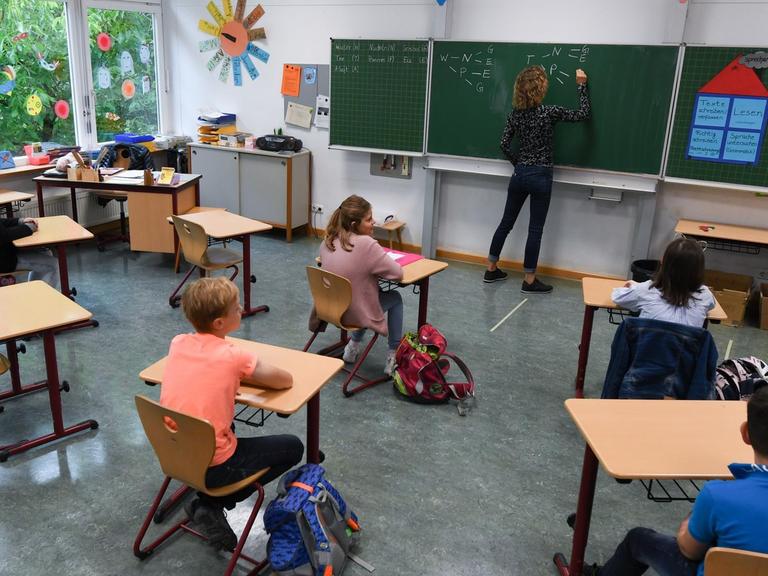 Schülerinnen und Schüler der Klasse 4c der Robert-Schumann-Grundschule sitzen mit Abstand zueinander im Unterricht bei ihrer Lehrerin Sylke Wassmann