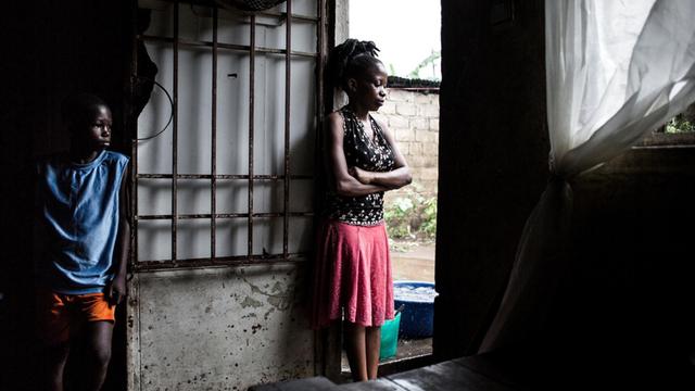 Im Kongo breitet sich die Cholera aus. Zwei junge Menschen stehen in einer Hütte in einem Slum und blicken durch die offene Tür nach draußen.
