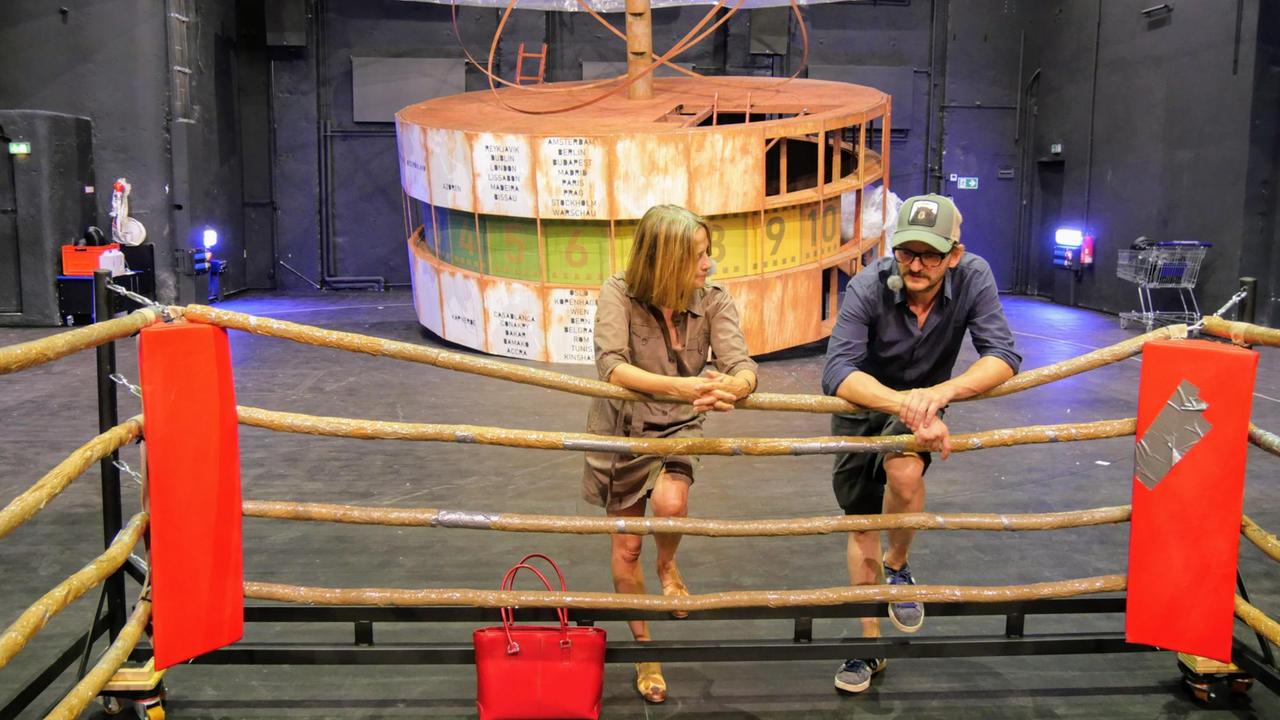 Gisela Steinhauer und Milan Peschel lehnen sich auf die Seile eines Boxrings, im Hintergrund ein Modell der Berliner Weltzeituhr Gisela Steinhauer und Milan Peschel lehnen sich auf die Seile eines Boxrings, im Hintergrund ein Modell der Berliner Weltzeituhr