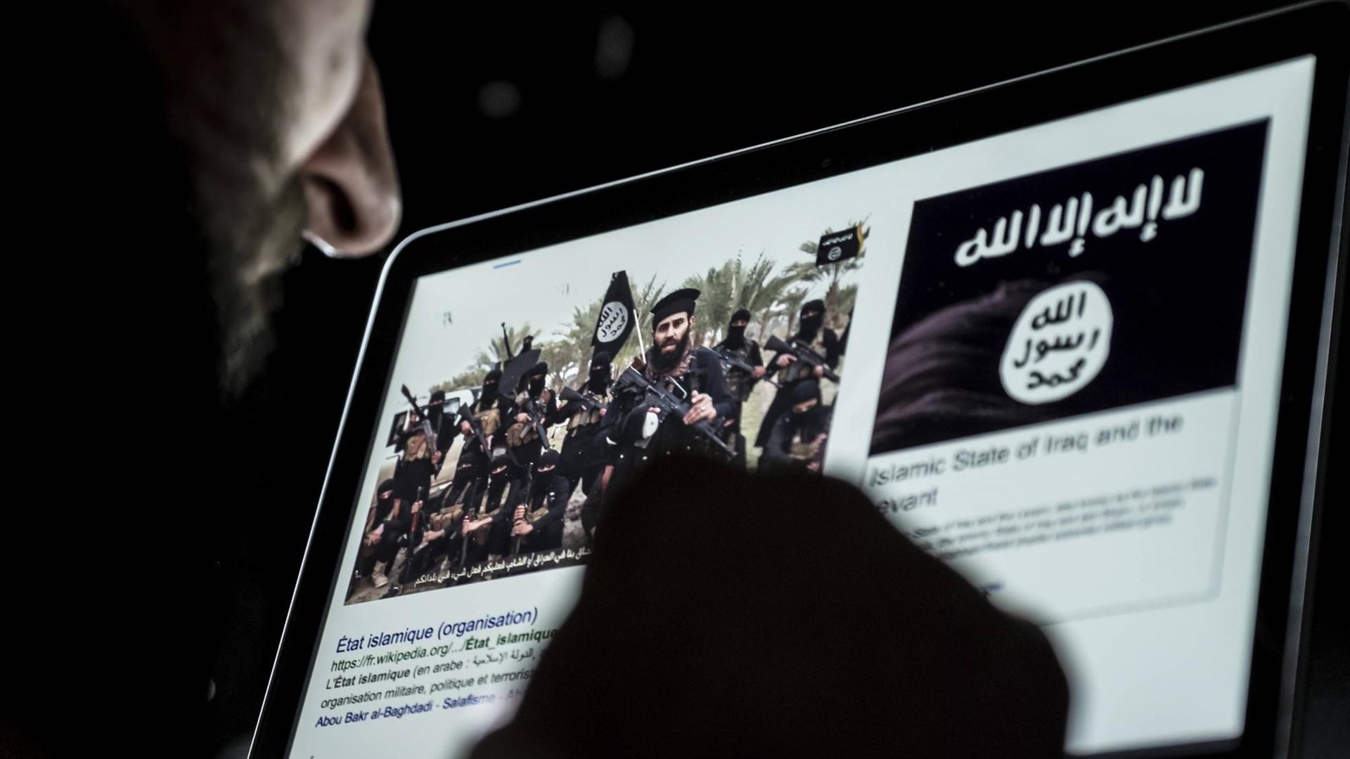 Ein Mann blickt auf einen Computerbildschirm mit der Flagge des sogenannten Islamischen Staates und einem Bild mit Kämpfern, die die Flagge des Islamischen Staates tragen. Ein Mann blickt auf einen Computerbildschirm mit der Flagge des sogenannten Islamischen Staates und einem Bild mit Kämpfern, die die Flagge des Islamischen Staates tragen.
