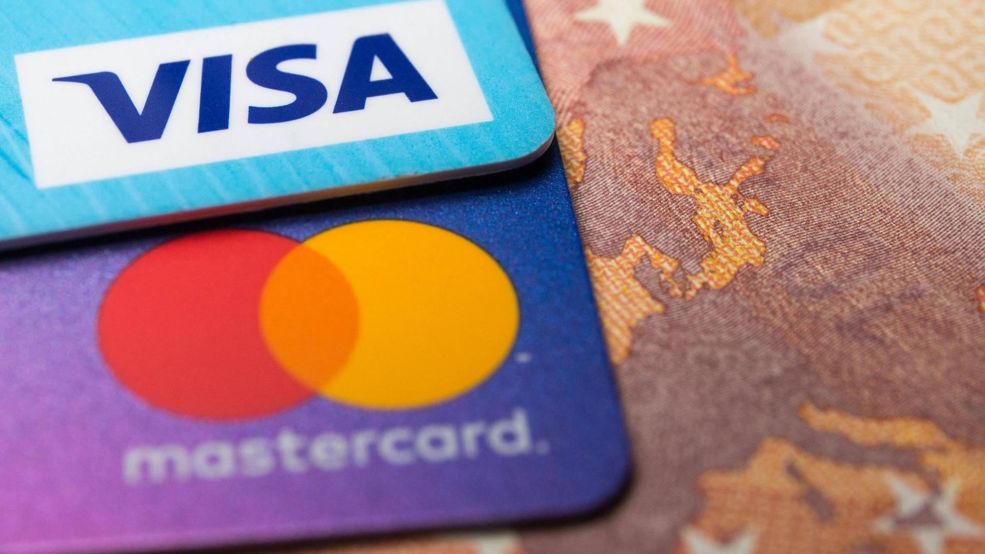 Eine Visa- und eine Mastercard-Kreditkarte auf einem 50-Euro-Schein