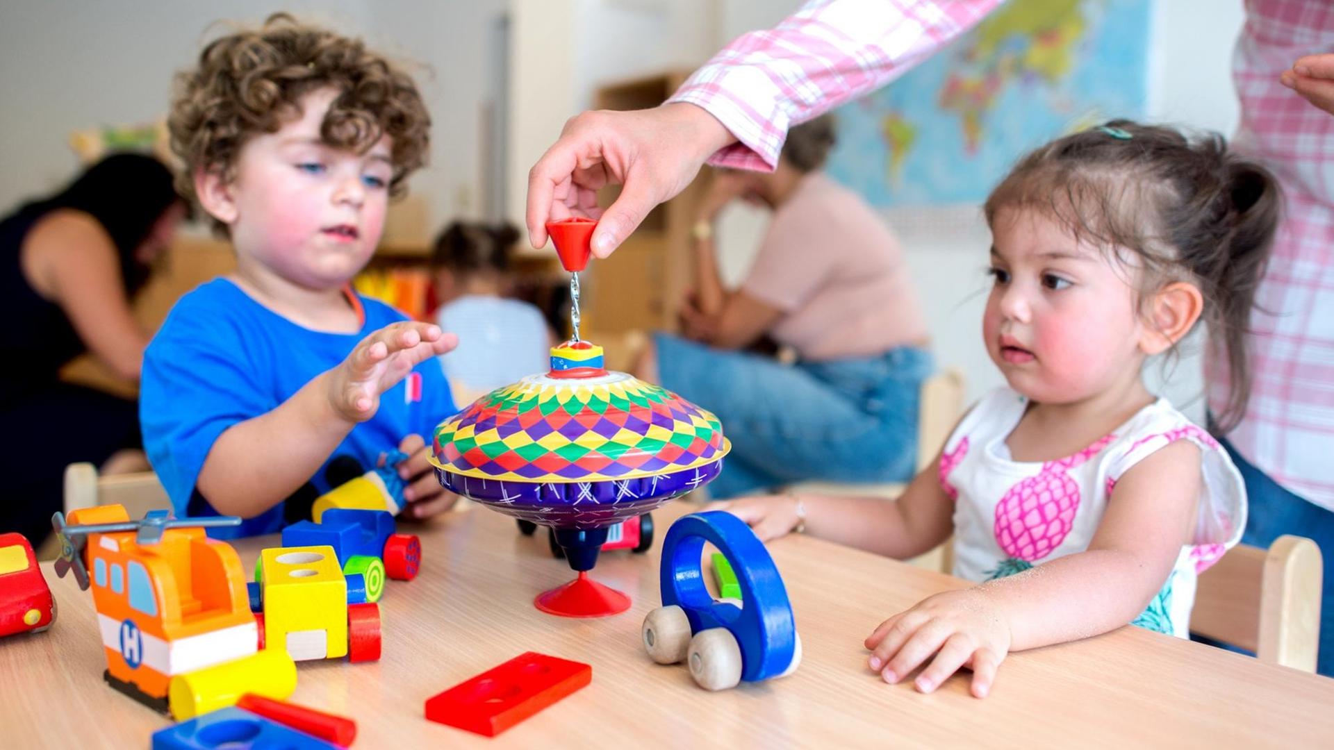 Zwei kleine Kinder spielen mit einem Kreisel Zwei kleine Kinder spielen mit einem Kreisel