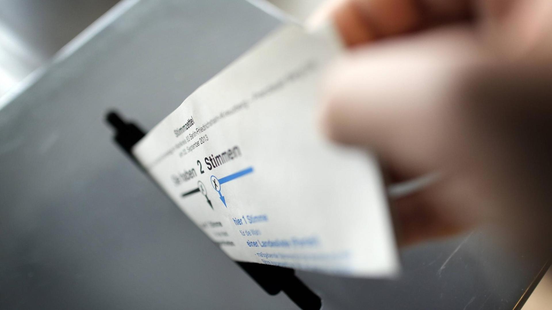 Ein Stimmzettel wird in eine Wahlurne gesteckt Ein Stimmzettel wird in eine Wahlurne gesteckt