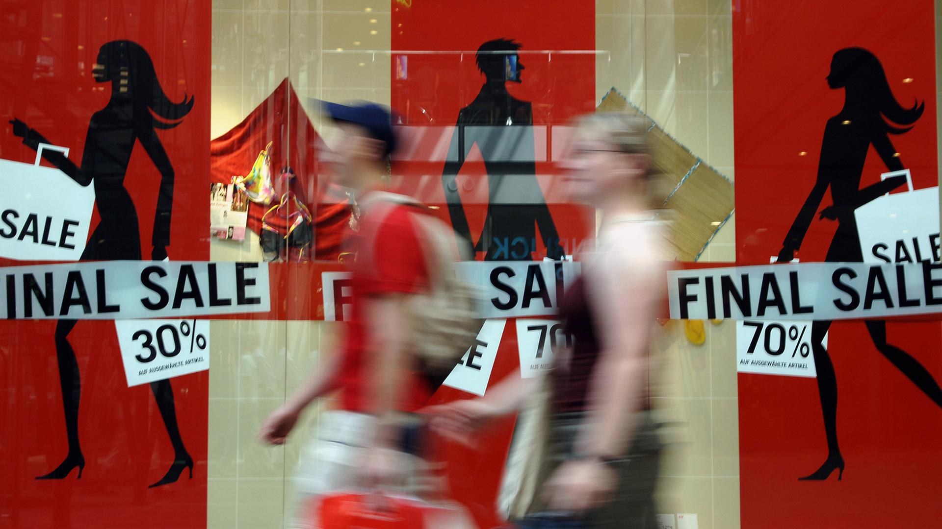 Zwei Passanten gehen in den Potsdamer Platz Arkaden in Berlin an einem Schaufenster vorbei, in dem mit hohen Preisnachlässen geworben wird. Zwei Passanten gehen in den Potsdamer Platz Arkaden in Berlin an einem Schaufenster vorbei, in dem mit hohen Preisnachlässen geworben wird.