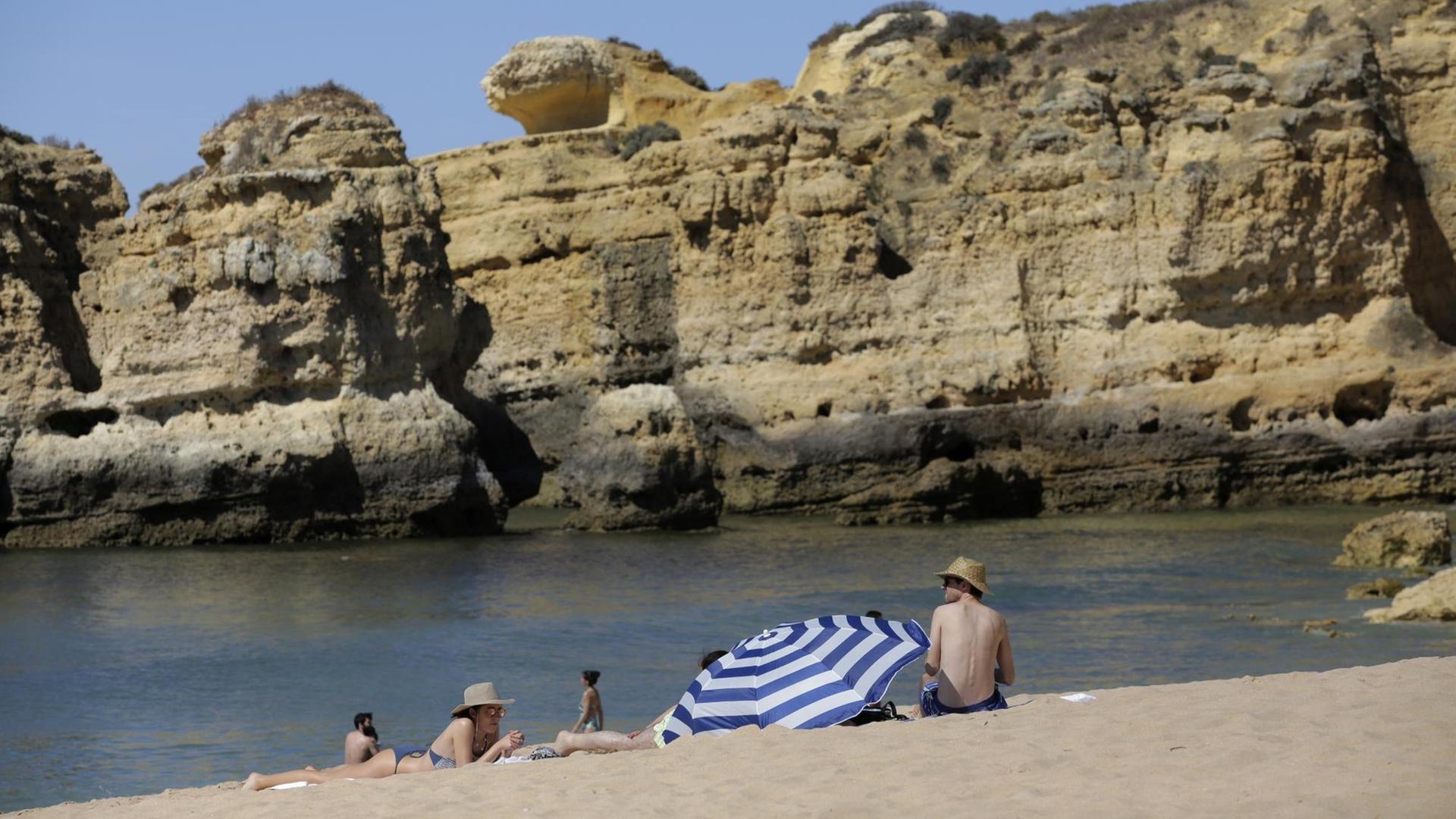Menschen sitzen an einem Strand in dem Land Portugal. Menschen sitzen an einem Strand in dem Land Portugal.