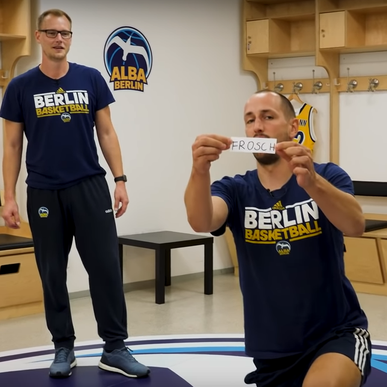 Zwei Sportler von Alba Berlin stehen in der Umkleide und schauen in die Kamera
