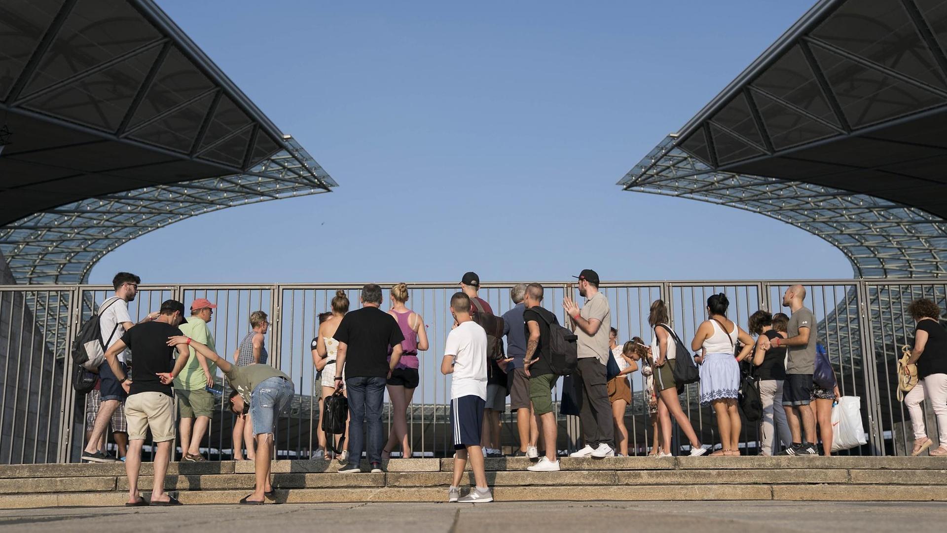 Besucher stehen vor der Umzäunung des Berliner Olympiastadions und blicken hinein. Besucher stehen vor der Umzäunung des Berliner Olympiastadions und blicken hinein.