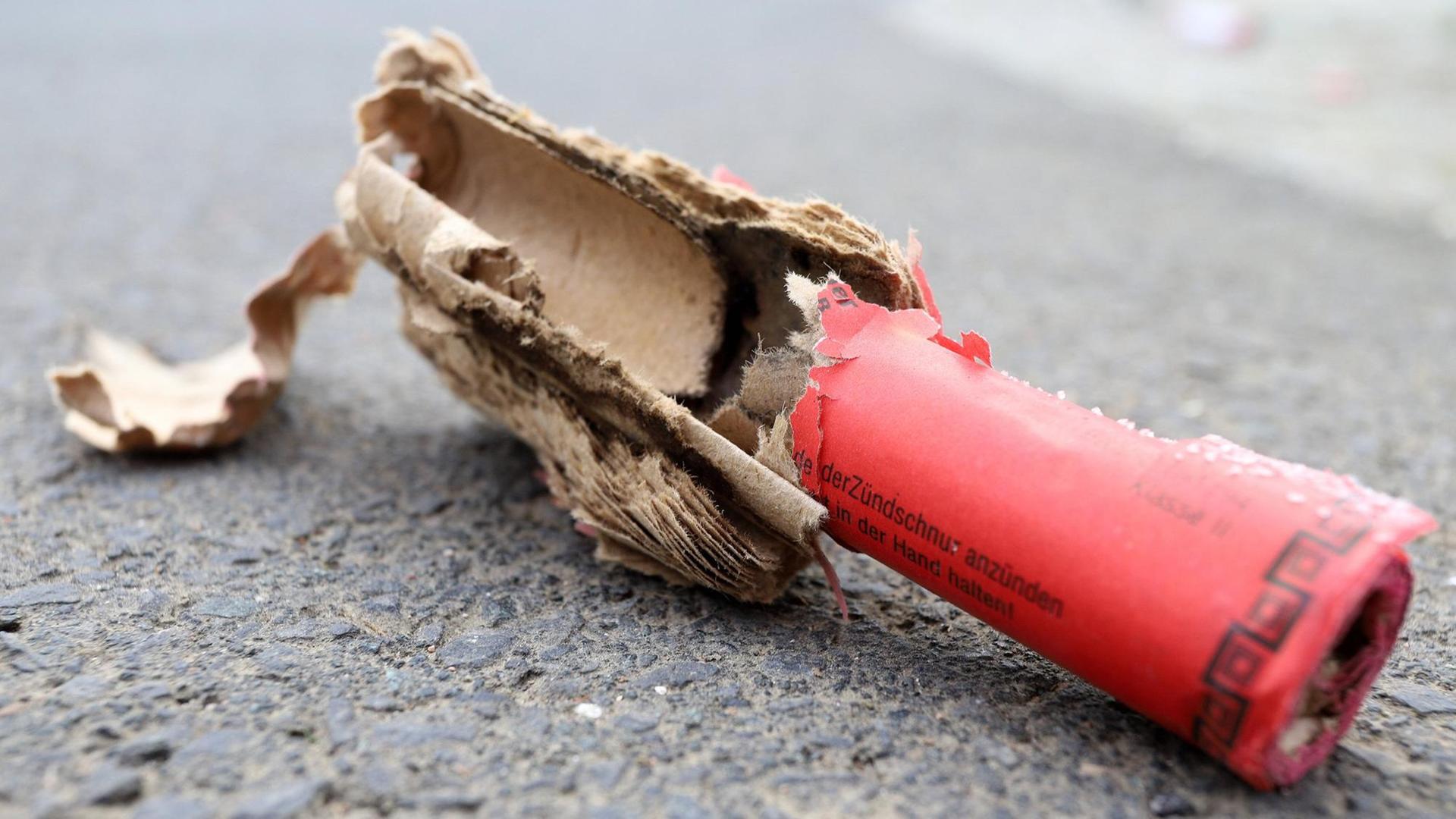 Ein explodierter roter Böller liegt auf der Straße. Ein explodierter roter Böller liegt auf der Straße.