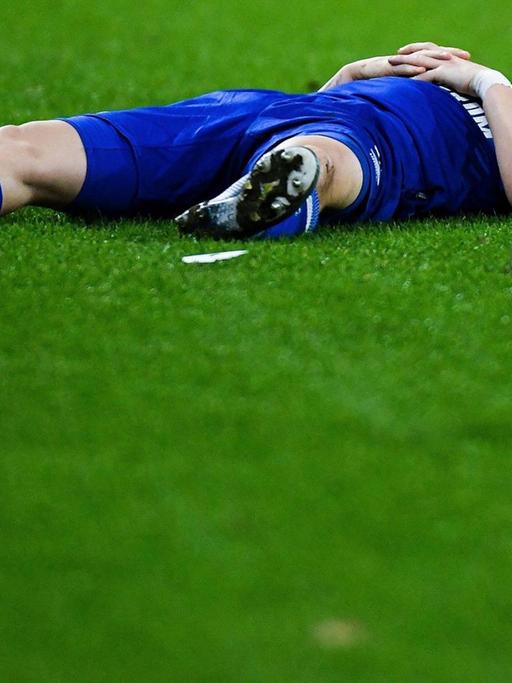 Ein Spieler im blauen Trikot liegt auf dem Rasen, neben ihm ein Fußball.