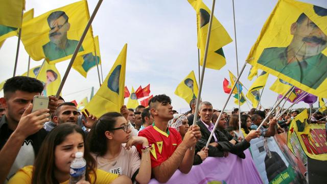 Kurden schwenken gelbe Fahnen mit Öcalan-Porträt