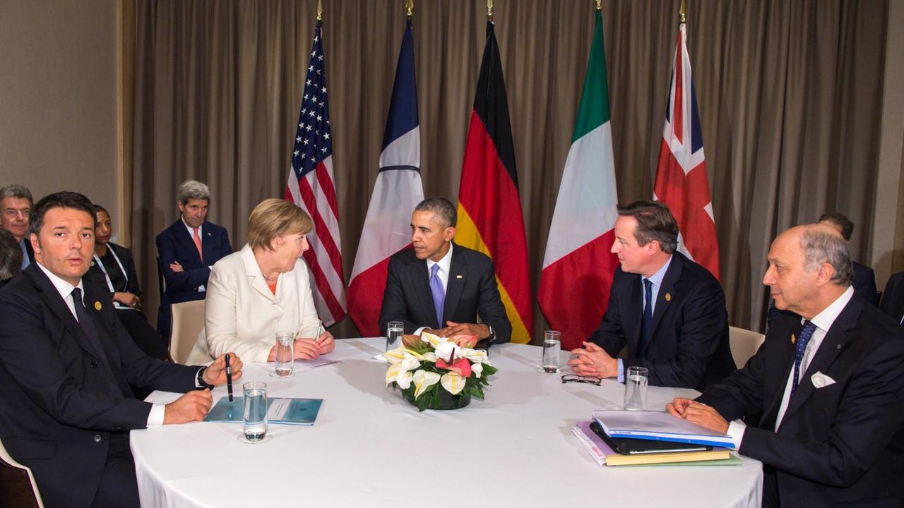 Renzi, Merkel, Obama, Cameron und Fabius sitzen an einem Tisch und reden, hinter ihnen die Flaggen ihrer Länder.