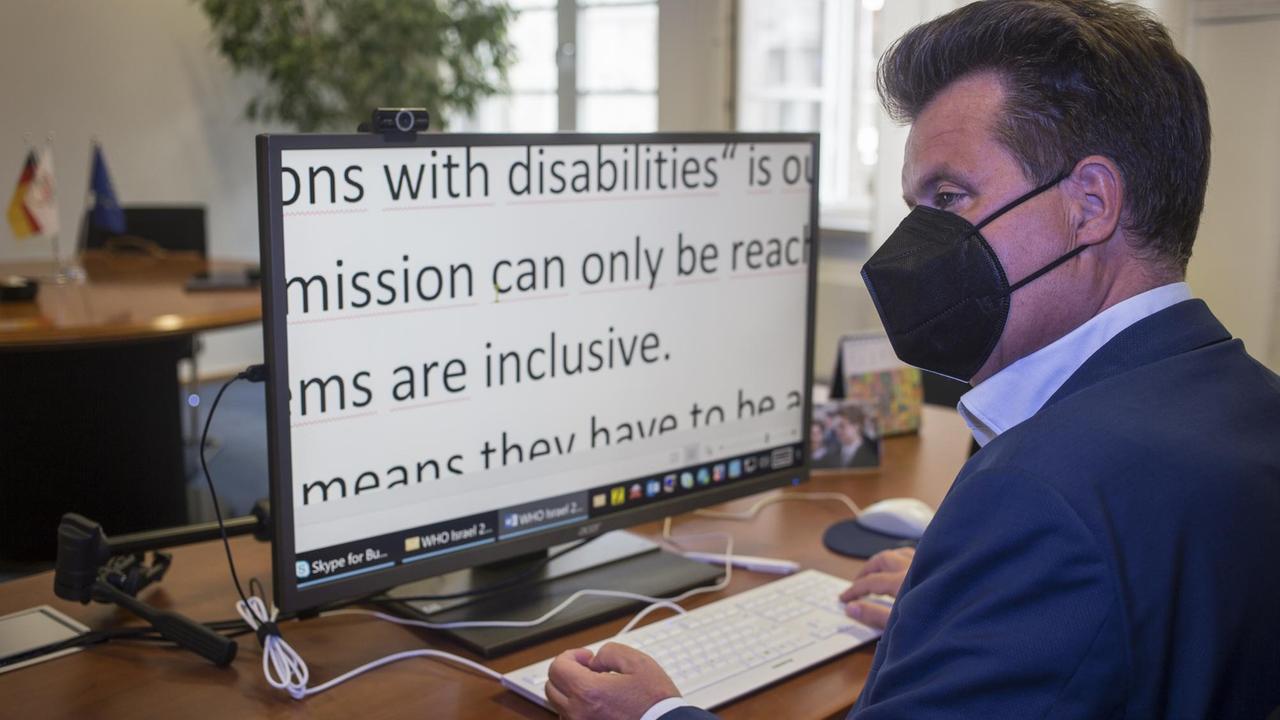 Jürgen Dusel, Behindertenbeauftragter der Bundesregierung, sitzt in seinem Büro am Computer. Mit dem ZoomText Programm auf seinem Bildschirm kann er den Text lesen.