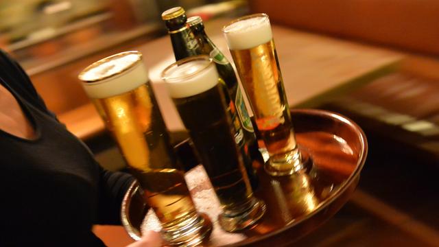 Eine Bedienung trägt am 29.10.2013 in Erfurt (Thüringen) in einem Lokal ein Tablett mit Bier.