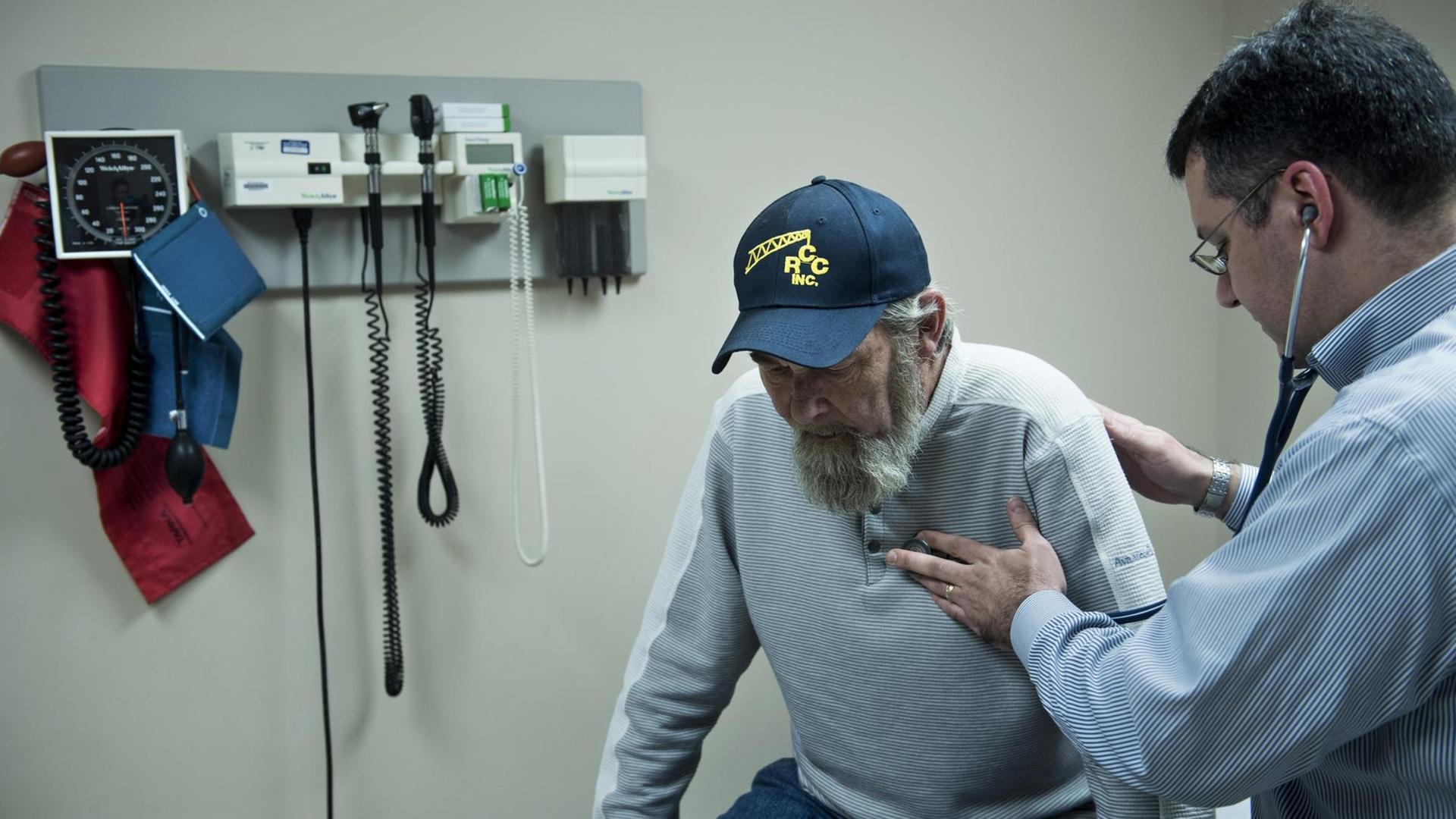 Das Bild zeigt einen Arzt, der einen älteren Mann behandelt. Das Foto stammt aus dem Clay-Battelle Community Health Center in Blacksville, West Virginia.
