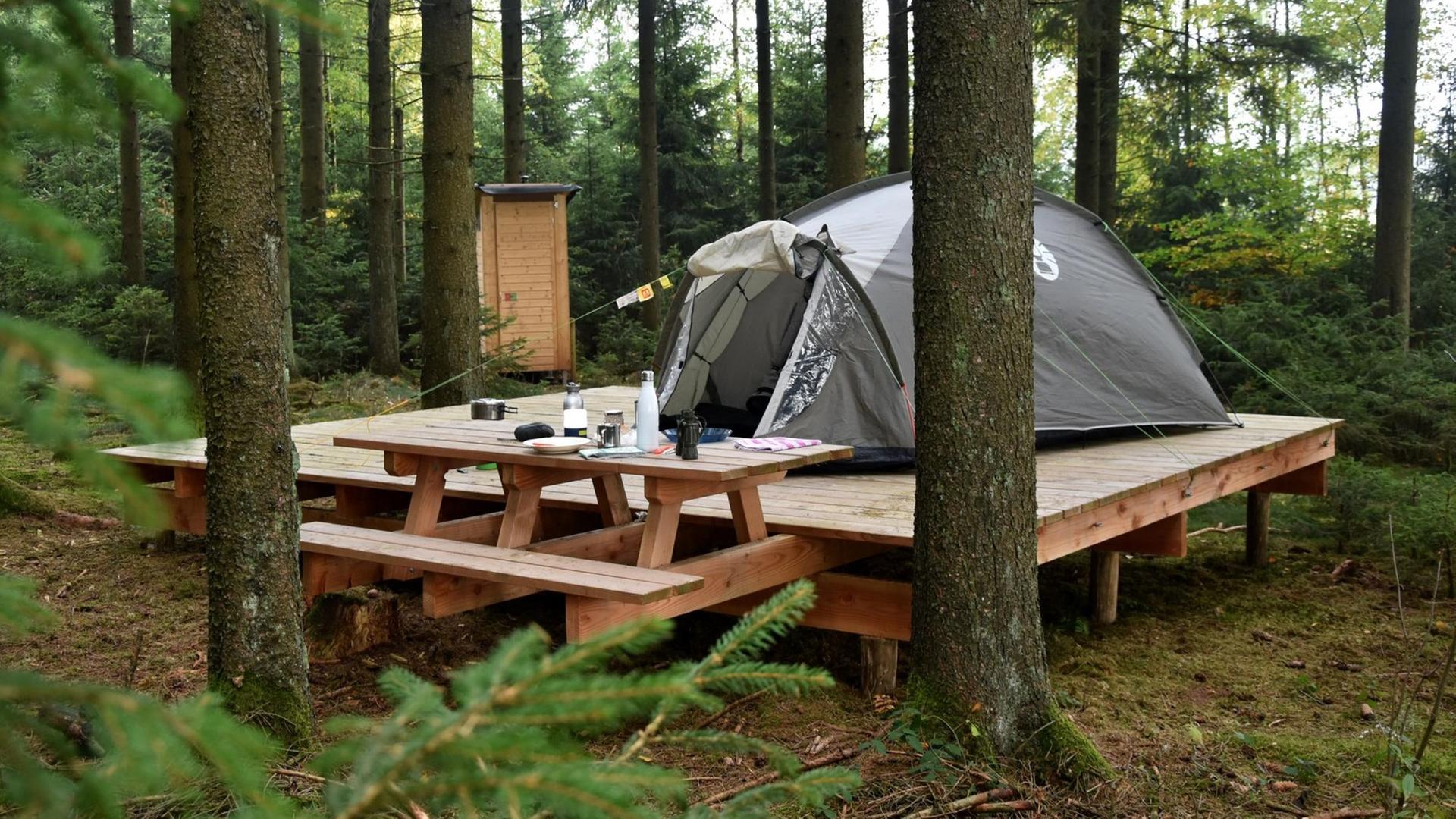 Ein Trekkingplatz im Nationalpark Eifel mit einem Zelt auf einer Holzplattform. Ein Trekkingplatz im Nationalpark Eifel mit einem Zelt auf einer Holzplattform.