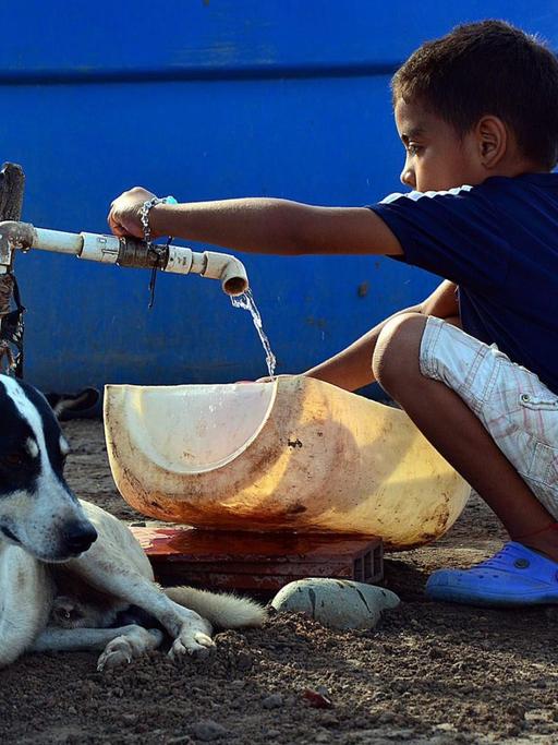Ein Junge in Kolumbien füllt Wasser aus einem Tank in ein Plastikgefäß.