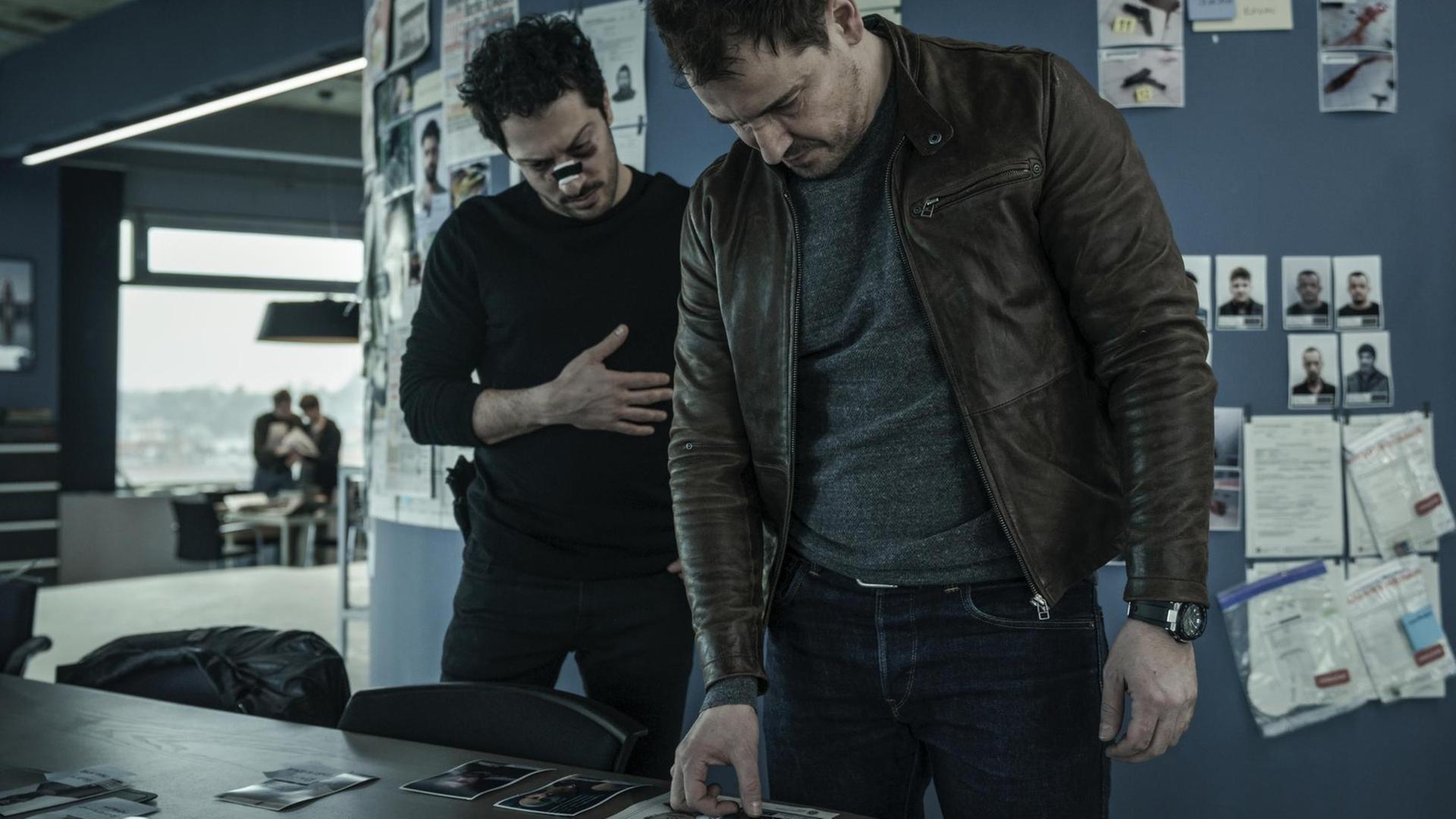 Zwei Schauspieler der Netflix-Serie "Dogs of Berlin" stehen an einem Schreibtisch Zwei Schauspieler der Netflix-Serie "Dogs of Berlin" stehen an einem Schreibtisch