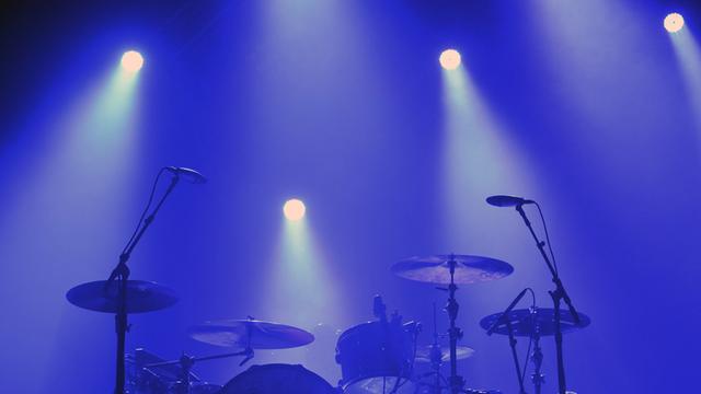 Ein Schlagzeug steht auf einer blau beleuchteten Bühne.