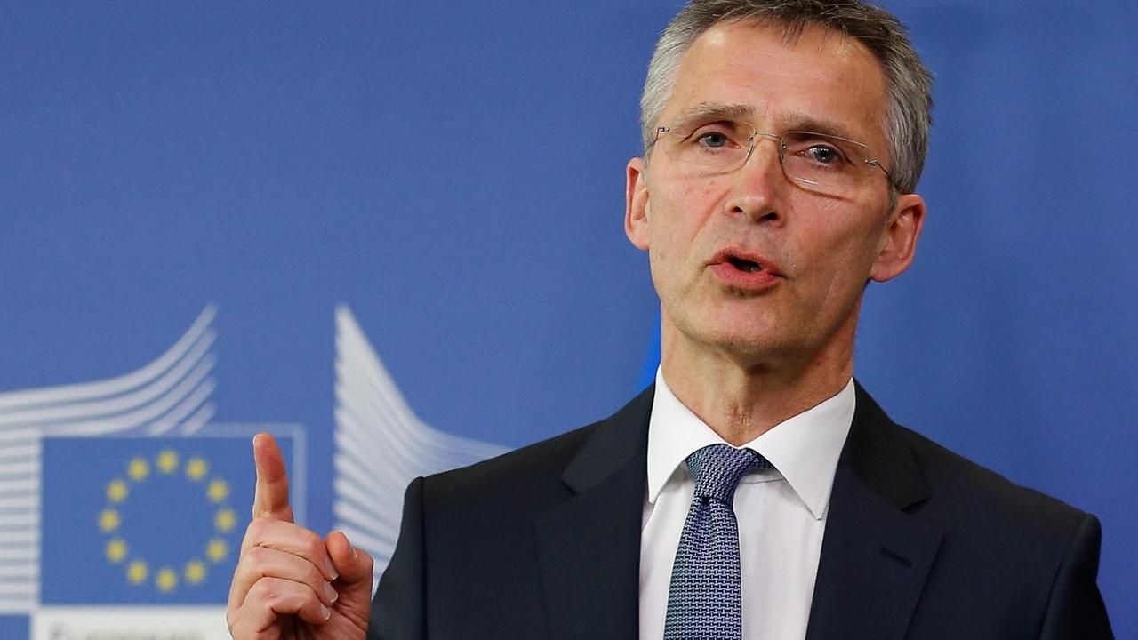 Stoltenberg steht vor einem blauen Backdrop der EU-Kommisssion, spricht und hebt den Zeigefinger. Stoltenberg steht vor einem blauen Backdrop der EU-Kommisssion, spricht und hebt den Zeigefinger.