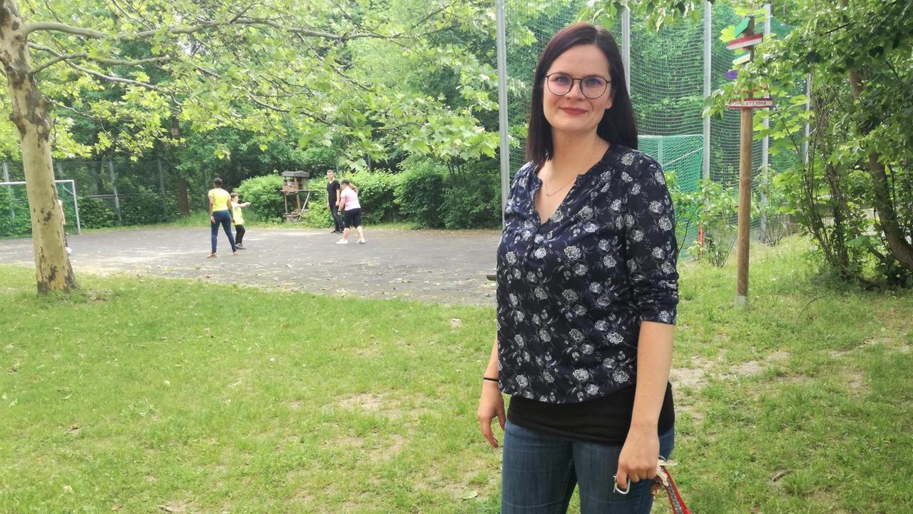 Jana Lepczyk steht in einem Park und blickt in die Kamera.