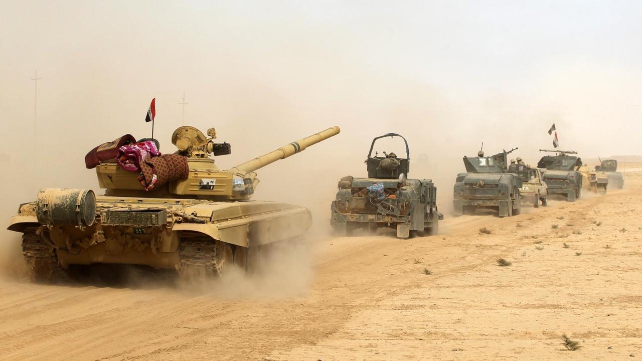 Panzer und Militärfahrzeuge rollen hintereinander durch den Wüstensand und ziehen Staubfahnenhinter sich her. Panzer und Militärfahrzeuge rollen hintereinander durch den Wüstensand und ziehen Staubfahnenhinter sich her.