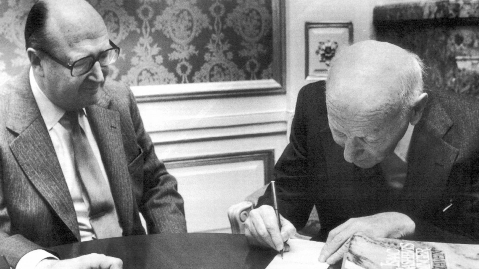 Der Vizevorsitzende der schwedischen Bank (Svenska Handelsbanken), Tore Browald (l), beobachtet den Literatur-Nobelpreisträger Isaac Bashevis Singer (r, "Mein Vater der Rabbi") beim Unterschreiben des Nobelpreis-Schecks am 11. Dezember 1978 in Stockholm.